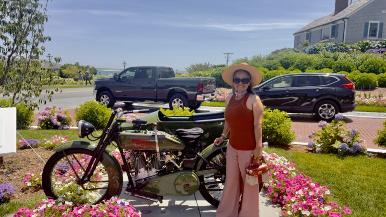 Aidalyn posing beside a vintage Harley-Davidson motorcycle in Cape Cod surrounded by hydrangeas and summer flowers.